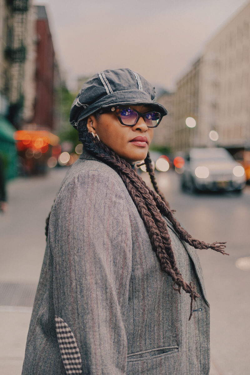 Victoria Spaulding-Burford, a design executive, photographed on a New York sidewalk in a tweed overcoat and newsboy cap, looking over her shoulder.